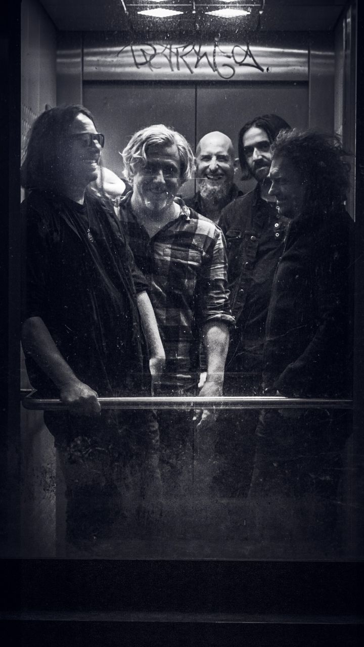 The same five band members in the lift, all laughing